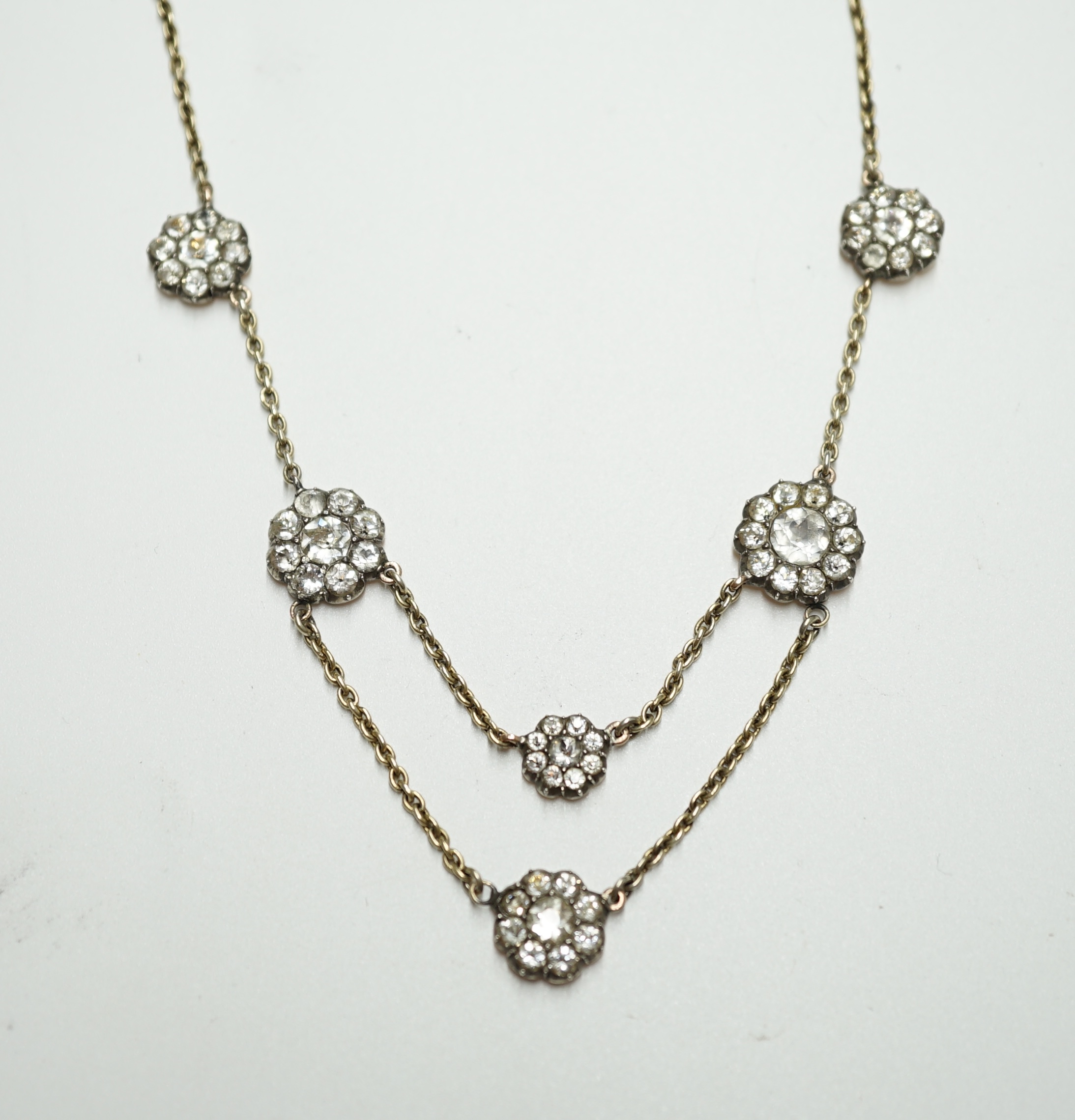 An early 20th century yellow metal and paste set multi flower head necklace, 39cm, gross weight 10.7 grams. Condition - poor to fair